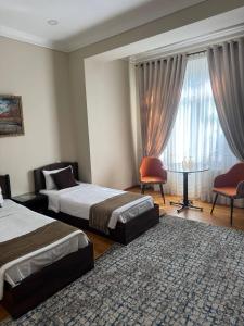 a hotel room with two beds and a table and a window at Shuxrat hotel in Chilanzar