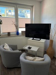 a living room with two chairs and a flat screen tv at Feriennest am Meer Warnemünde in Warnemünde