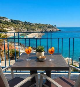 a table with two wine glasses on a balcony with the ocean at Maré Rooms Castro in Castro di Lecce