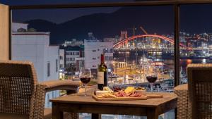 a table with a plate of food and glasses of wine at Tongyeong Present Gamsung Pension in Tongyeong