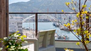 a balcony with two chairs and a view of a harbor at Tongyeong Present Gamsung Pension in Tongyeong
