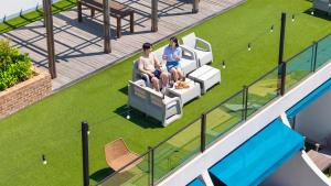 two people sitting on a couch on the balcony of a house at Tongyeong Present Gamsung Pension in Tongyeong +3 photos