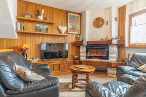 a living room with two leather chairs and a fireplace at Chalet & SPA Privata - Baita al Frassino, Ospitar in Vignola +26 photos