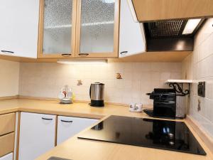 a kitchen with white cabinets and black appliances at ElvesHome - Alpine Stay Apartments in Predazzo