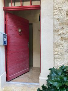 a red door of a building with a dog on it at Petit cocon à 10min d'Avignon in Pujaut