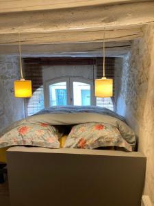 a bed with two pillows and two lights above it at Petit cocon à 10min d'Avignon in Pujaut