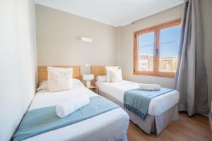 two beds in a room with a window at CARABELA 94 in Alcudia +9 photos