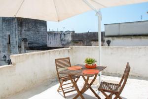a table with two chairs and an umbrella on a roof at Felline centro storico in Felline