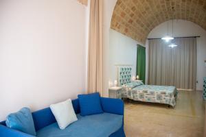 a living room with a blue couch and a bed at Felline centro storico in Felline