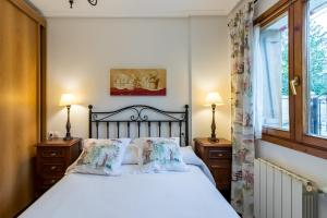 a bedroom with a bed and two lamps and a window at Las Camelias in Argoños
