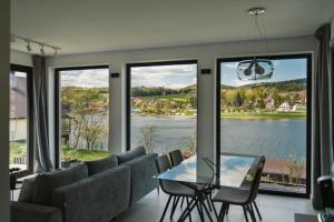 a living room with a table and chairs and a view of a lake at Gródek & Ogródek in Gródek Nad Dunajcem
