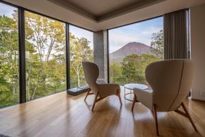 a room with two chairs and a table and large windows at Kozue in Kutchan