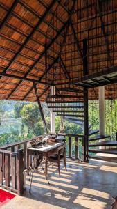 a room with a table on a deck with a view at T Stop Farmhouse Coorg in Kurchi