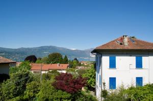 a white house with blue windows in a village at Casa Corten, Vista Lago in Cerro Lago Maggiore