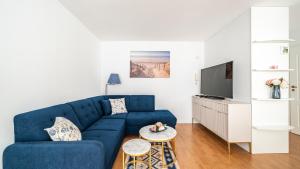 a living room with a blue couch and a tv at Na Wydmie, Sun & Snow in Ustka