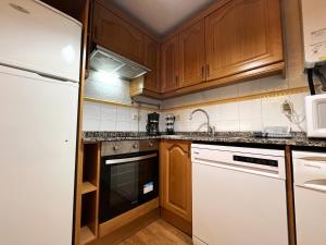 a kitchen with wooden cabinets and a white refrigerator at AC Apartaments Canillo in Canillo