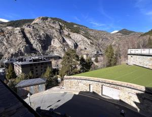 a building with a green field in front of a mountain at AC Apartaments Canillo in Canillo