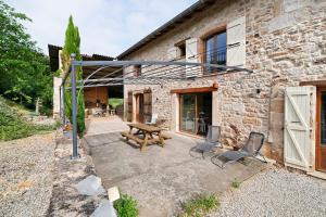 a patio with a wooden table and chairs in front of a building at Chambres D'hôtes La Boriette in Castelnau-de-Montmiral