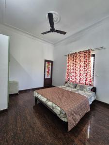 a bedroom with a bed and a ceiling fan at meadowell homestay in Kizhake Chālakudi