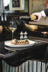 eine Person, die ein Glas Wein über einen Teller mit Essen gießt in der Unterkunft Hotel d'Angleterre in Genf