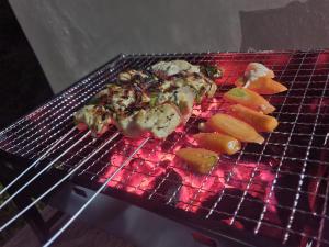 a grill with meat and vegetables cooking on it at Chez Rasoa Andasibe in Moramanga
