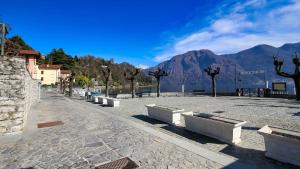 a row of benches on a street with a mountain at Historic Borgo Lake Como Campidoglio 3 in Lenno