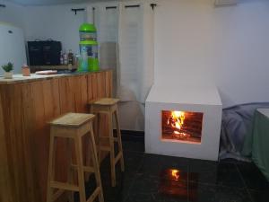 a fireplace in a kitchen with stools and a stove at Chez Rasoa Andasibe in Moramanga