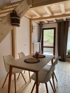 a dining room with a table and white chairs at Casa Lucia in Dămuc