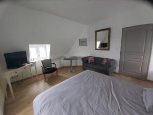 a bedroom with a bed and a couch and a television at Manoir Saint-Eloi in Noyon