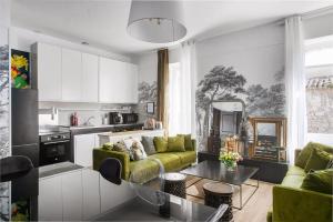 a living room with a green couch and a kitchen at Alombre in Lectoure