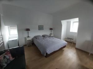 a bedroom with a bed and two windows and a couch at Manoir Saint-Eloi in Noyon