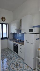 a kitchen with white appliances and a tile floor at Seaview Home Bacoli in Bacoli