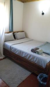 a bedroom with a large bed with white sheets at Chez Rasoa Andasibe in Moramanga