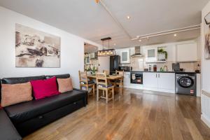 a living room with a black couch and a kitchen at Group-Friendly Flat - 3 Beds, a Sofa Bed & Parking in Andover