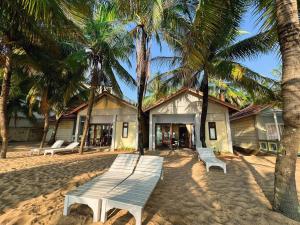 a group of benches on a beach with palm trees at Cửu Long Beach Phú Quốc in Phú Quốc