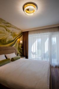 a bedroom with a large white bed and a chandelier at Galant Apartments in Cluj-Napoca