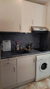 a kitchen with white cabinets and a washing machine at Appartement balcon proche mer in Saint Pierre La Mer