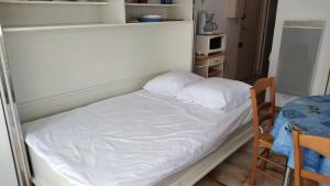 a small bed with two pillows in a room at Appartement balcon proche mer in Saint Pierre La Mer