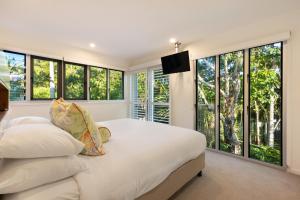 a bedroom with large windows and a bed with a television at East On Byron Bay Apartments in Byron Bay +99 photos
