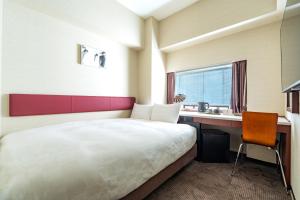 a hotel room with a bed and a desk and a sink at Koraku Garden Hotel Tokyo in Tokyo