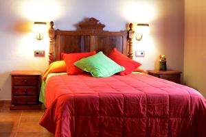 a bedroom with a large bed with red and green pillows at Casa Domingo in Manzanera