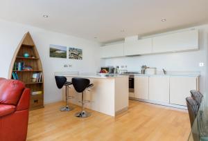 a kitchen with white cabinets and a red couch at 11 Zinc in Newquay in Newquay
