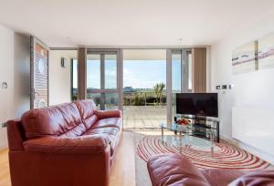 a living room with a leather couch and a television at 11 Zinc in Newquay in Newquay