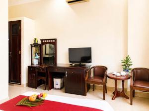 a living room with a television and a desk with chairs at Cửu Long Beach Phú Quốc in Phú Quốc