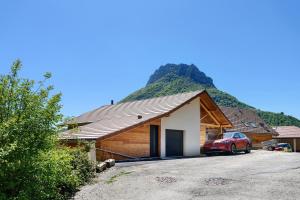 a house with a car parked in front of a mountain at Fenêtre sur le Neron in Quaix