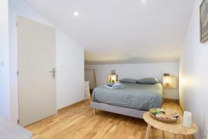 a white bedroom with a bed and a table at Fenêtre sur le Neron in Quaix