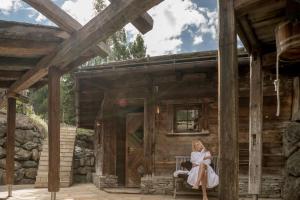 a woman sitting on a bench outside of a cabin at Hotel Nevada in Samnaun