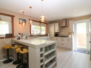 a kitchen with white cabinets and a large island with bar stools at Crown Cottage in Dunfermline