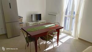 a kitchen with a wooden table with chairs and a refrigerator at Medoro Gioiosa 2 in Gioiosa Marea