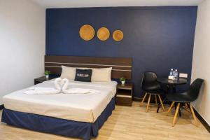a bedroom with a bed and two chairs and a table at Get Inn Hotel at 1 Capital Holdings in Gua Sai